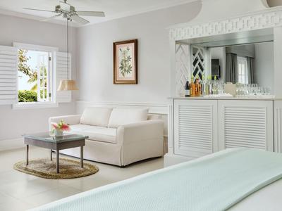 Elegantes Hotelzimmer mit weißem Sofa, Fenster mit Holzläden und dekorativem Spiegel.