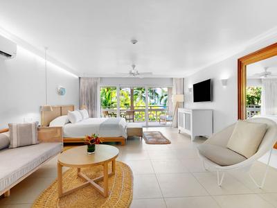 Helles Hotelzimmer mit großem Fenster, Bett, Sofa und modernem Sessel.
