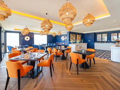 Modernes Restaurant mit orangen Stühlen und hölzernen Lampen in hell gestaltetem Raum