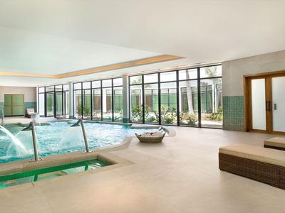 Moderner Innenpool mit großen Glasfenstern, Liegen und natürlicher Beleuchtung.