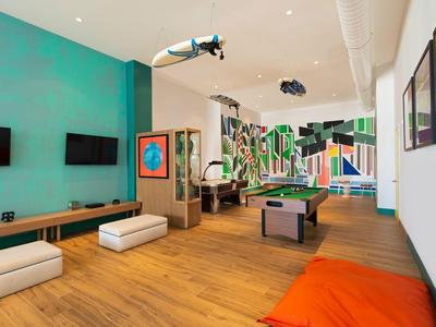 Moderner Gesellschaftsraum mit Billardtisch, Sitzkissen und Sportsurfbrett an der Decke.