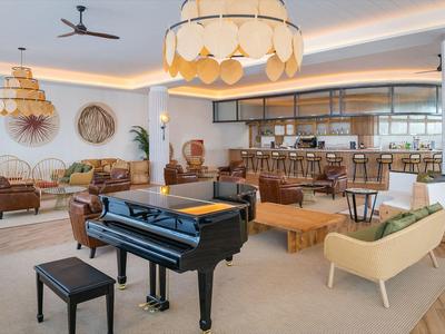 Elegante Hotellounge mit schwarzem Flügelklavier, stilvollen Möbeln und großen Leuchten.