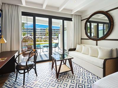 Modernes Hotelzimmer mit Schreibtisch, Sofa und Balkon mit Aussicht auf das Meer.