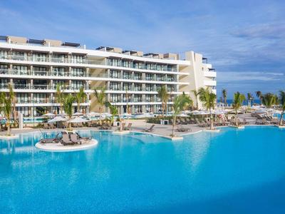 Großes Hotel mit mehreren Etagen und großem Pool im Freien bei sonnigem Wetter.