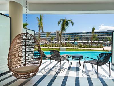 Balkon mit Hängesessel und Stühlen mit Blick auf Pool und Palmen in Hotelumgebung