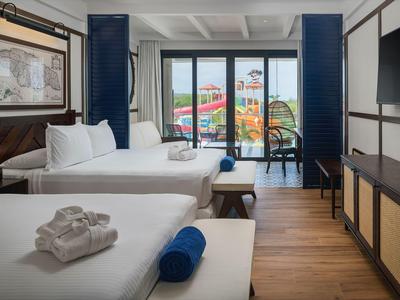 Hotelzimmer mit zwei Betten, Blick auf Wasserrutschen durch große Fenster