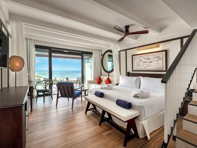 Modernes Hotelzimmer mit Doppelbett, Meerblick und Sitzbereich auf Holzfußboden.