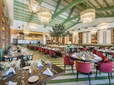 Elegantes Restaurant mit grünen und roten Akzenten, dekorativen Lampen und eingedeckten Tischen.