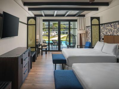 Modernes Hotelzimmer mit zwei Betten, TV, Balkon und Blick auf den Pool.