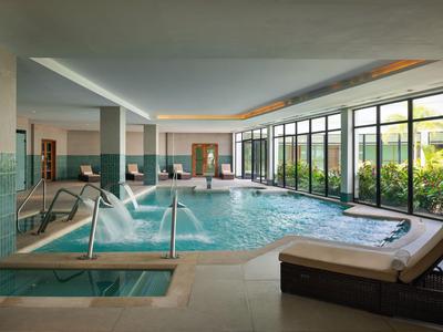 Innenpool mit Liegestühlen und großen Fenstern in einem Hotelbereich