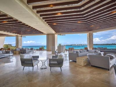Offene Hotel-Lounge mit gemütlichen Stühlen und Blick auf das blaue Meer bei klarem Himmel.