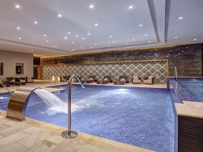 Moderner Innenpool mit Wasserfall und bequemen Liegestühlen in einem Hotel.