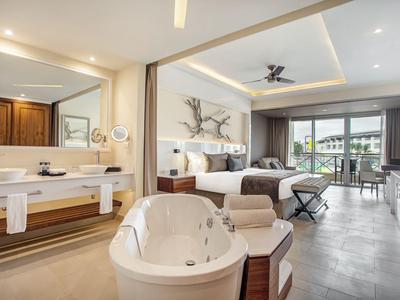 Moderne Hotel-Suite mit freistehender Badewanne, Doppelbett und Balkon mit Aussicht.