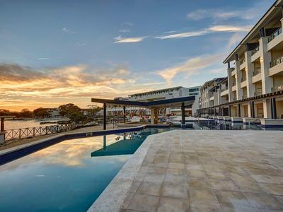 Moderner Hotelpool mit Liegestühlen und Sonnenuntergang am Meer.