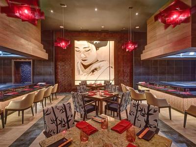 Modern eingerichtetes Restaurant mit holzverkleideten Wänden und roter Beleuchtung.