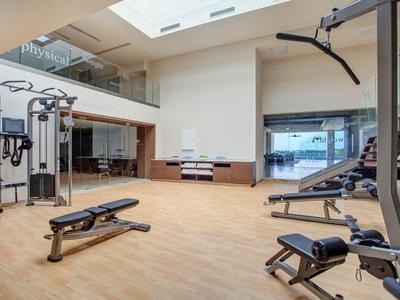 Moderner Fitnessraum mit verschiedenen Trainingsgeräten und leichter Deckenbeleuchtung.