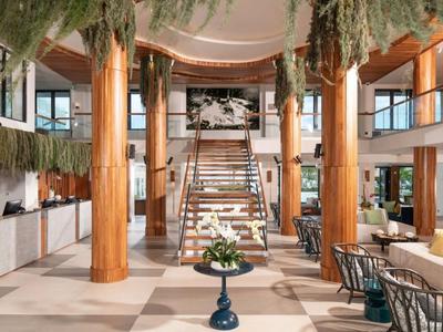 Moderner Hotellobby mit großzügigem Treppenhaus und grüner Hängedekoration