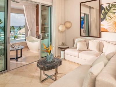 Heller Wohnbereich mit Sofas, Tisch und Blick auf Terrasse mit Pool und Meer.