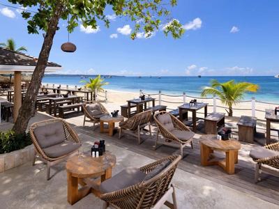 Strandbar mit Stühlen und Tischen, Blick auf den Sandstrand und das Meer bei sonnigem Wetter