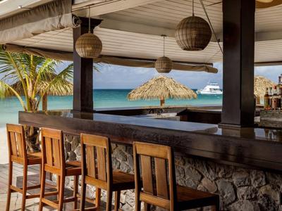 Offene Strandbar mit Holzstühlen und Blick auf das Meer und Palmen