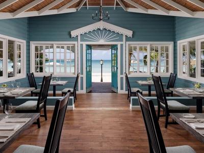 Elegantes Restaurant mit hohen Stühlen und großen Fenstern in blau-weißem Design.