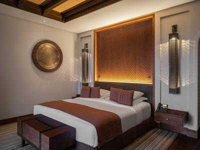 Cozy hotel room with a double bed, warm lighting, wooden ceiling, and modern decor.