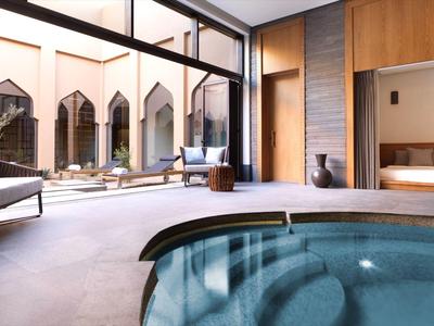 Indoor pool with lounge chairs and outdoor seating in a modern hotel environment.