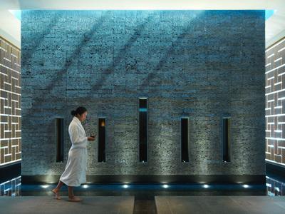 Spa corridor with bright geometric wall panels and person in white robe walking by.