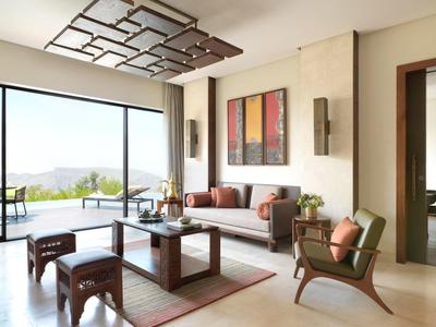 Bright hotel lounge with modern furniture and large glass doors opening to a terrace with a scenic view.