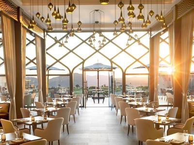 Spacious dining room with modern chairs, large windows, and sunset view.
