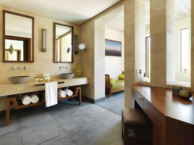 Modern hotel bathroom with double sinks, large mirrors, and view into a bright lounge area.