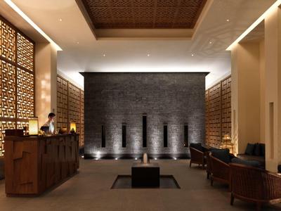 Modern hotel lobby with wooden reception desk, decorative panels, and cozy seating area.