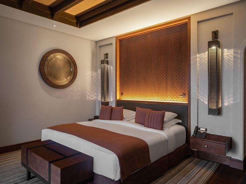 Cozy hotel room with a double bed, warm lighting, wooden ceiling, and modern decor.