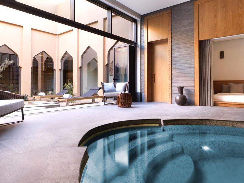 Indoor pool with lounge chairs and outdoor seating in a modern hotel environment.