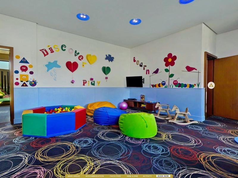 Bright, colorful children's playroom with foam blocks, seating, toys, and playful wall decorations.