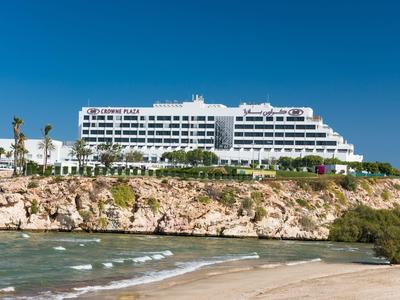 Großes, weißes Gebäude auf Felsen mit grünen Palmen und blauem Himmel im Hintergrund.