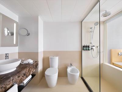 Modernes Badezimmer mit Waschbecken, Toilette, Bidet und begehbarer Dusche im Hotelzimmer.