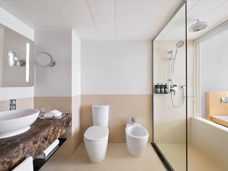 Modernes Badezimmer mit Waschbecken, Toilette, Bidet und begehbarer Dusche im Hotelzimmer.