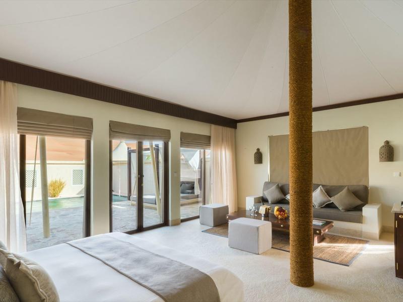 Helles Schlafzimmer mit großen Fenstern, modernem Bett, Sitzgelegenheiten und Zugang zur Terrasse.