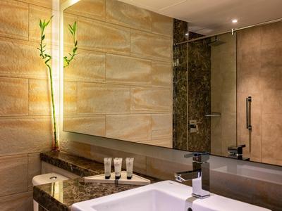 Nowoczesne lustro łazienkowe z umywalką i kosmetykami na marmurowym blacie.