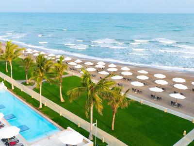 Kurort plażowy z basenem, palmami i parasolami przy morzu