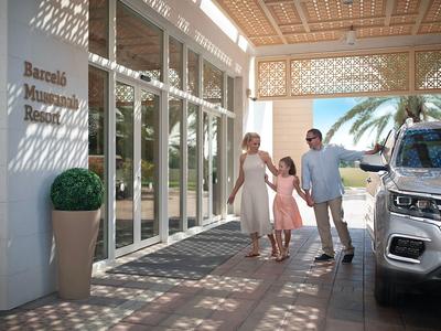 Familie mit Kind verlässt einen Hotel-Eingang bei Sonnenschein