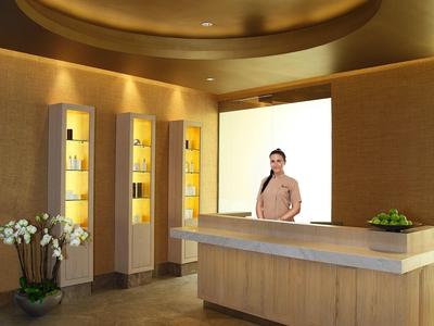 Nowoczesna recepcja z ladą i ciepłym oświetleniem, ozdobiona roślinami i kwiatami.