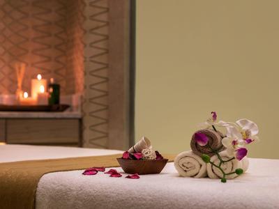 Przytulne spa z pachnącymi świecami, ręcznikami i orchideami na stole do masażu.