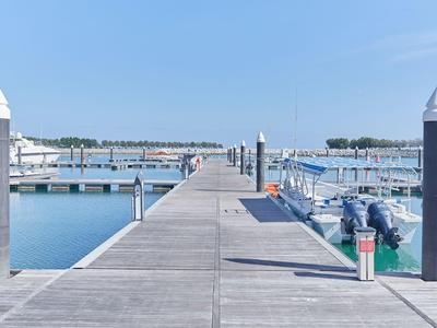 Steg im Hafen mit Booten und klarem Himmel im Hintergrund.