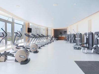 Heller Fitnessraum mit Cardiogeräten und Kraftstationen neben großen Fenstern.