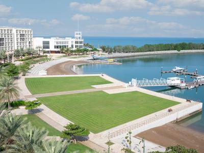 Luksusowy kurort z białym hotelem, dużym trawnikiem i mariną nad morzem.