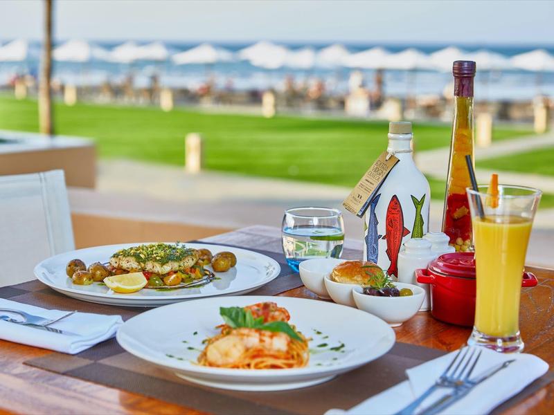 Stolik z widokiem na morze, serwowany z napojami i różnymi potrawami.