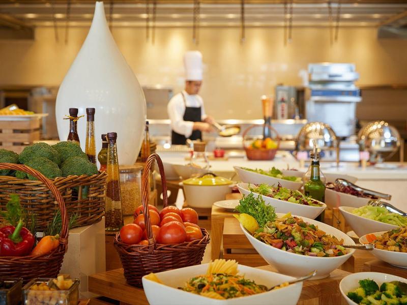 Bufet z świeżymi warzywami, sałatkami i butelkami oleju w kuchni hotelowej.