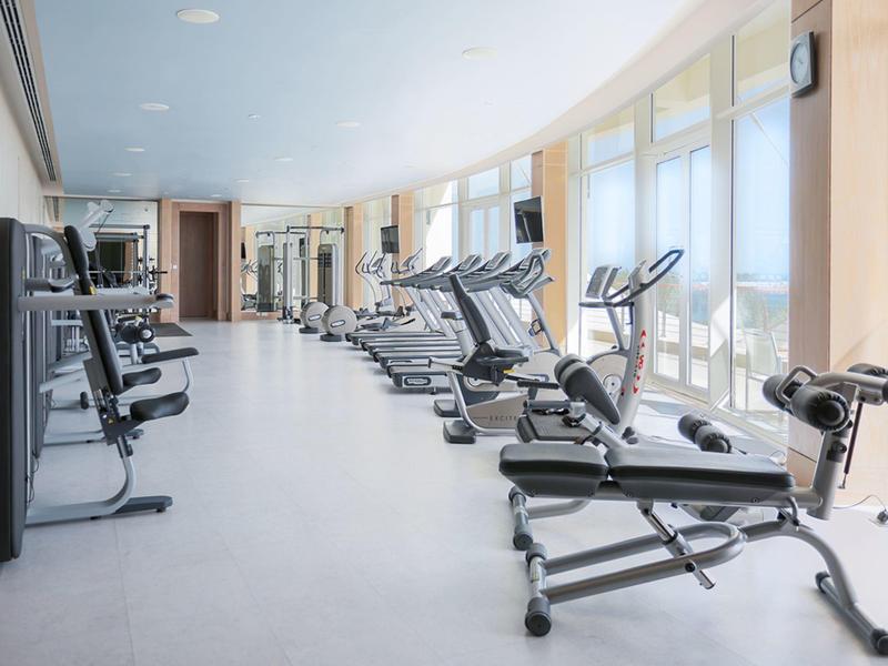 Jasna siłownia z nowoczesnym sprzętem i dużymi oknami z widokiem.